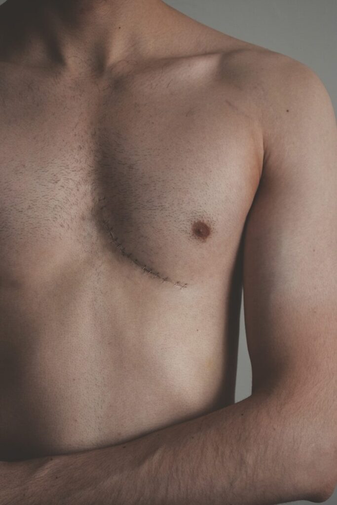 topless man standing near white wall